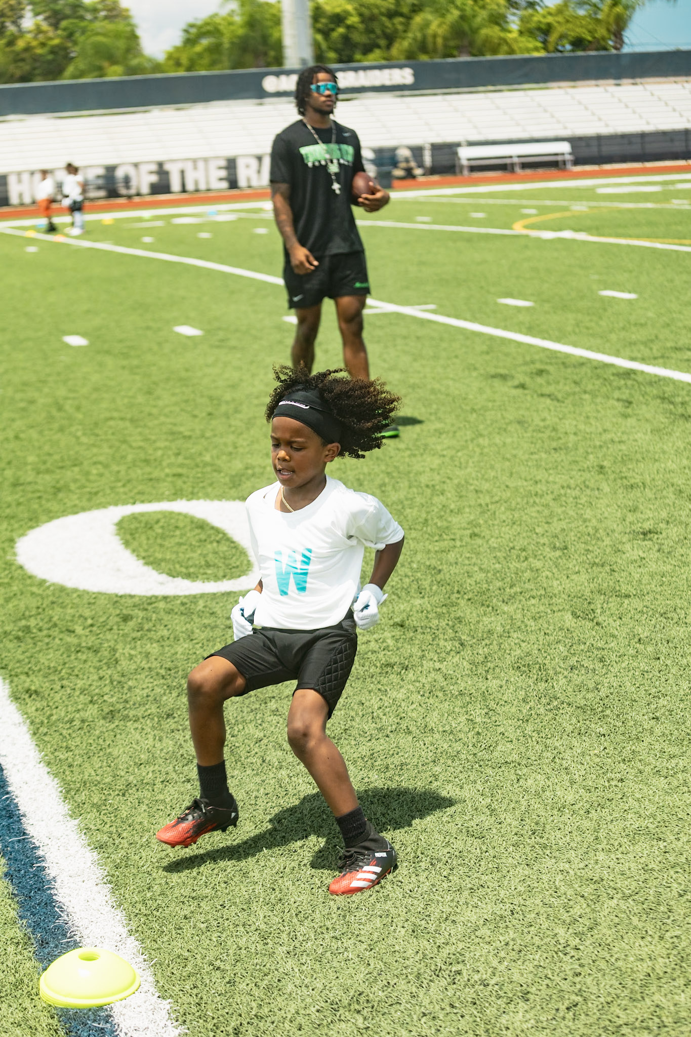 Young athlete cutting through a cone drill at the WeTrain youth football camp