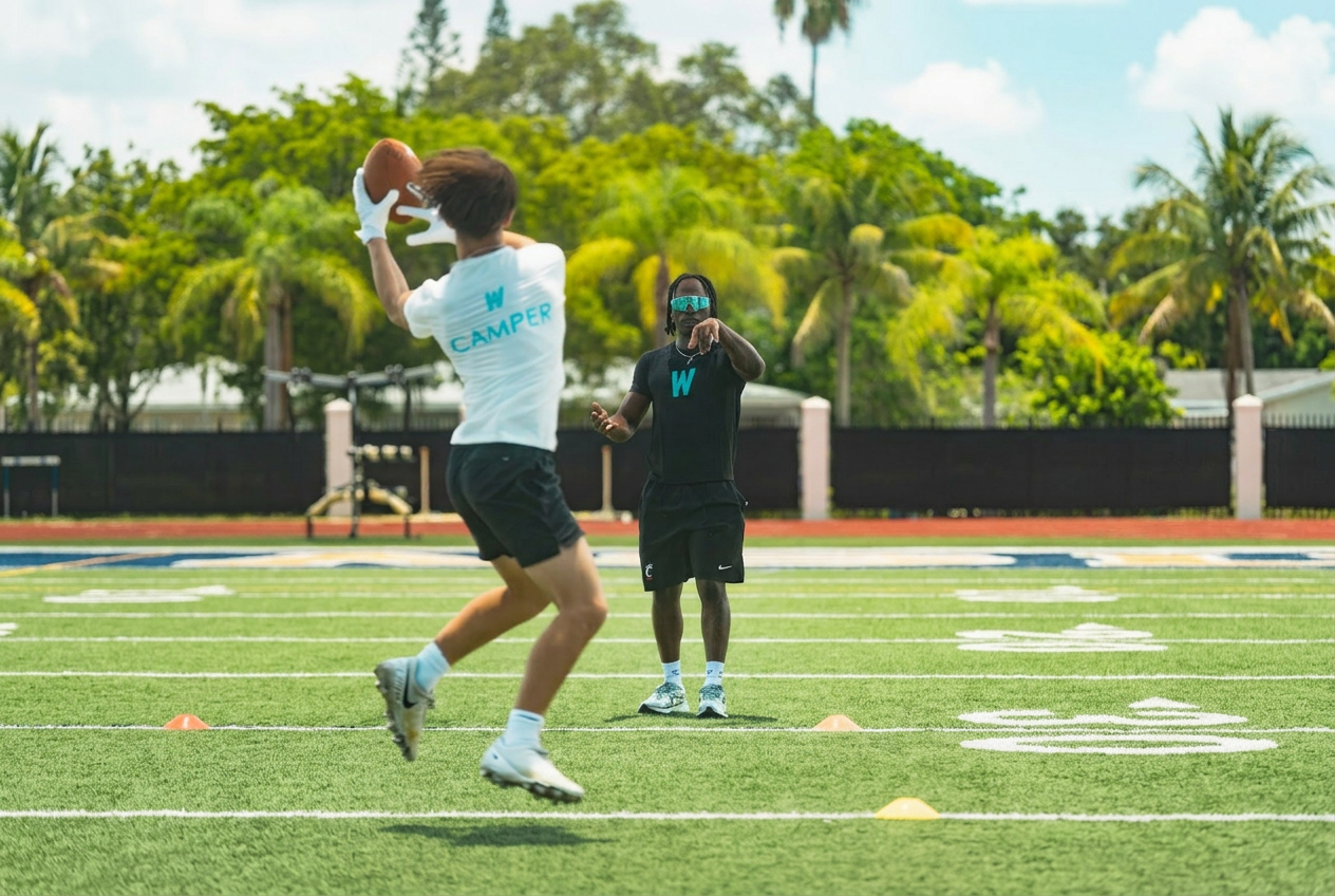 WeTrain trainer coaching a young camper catching a pass during a route drill