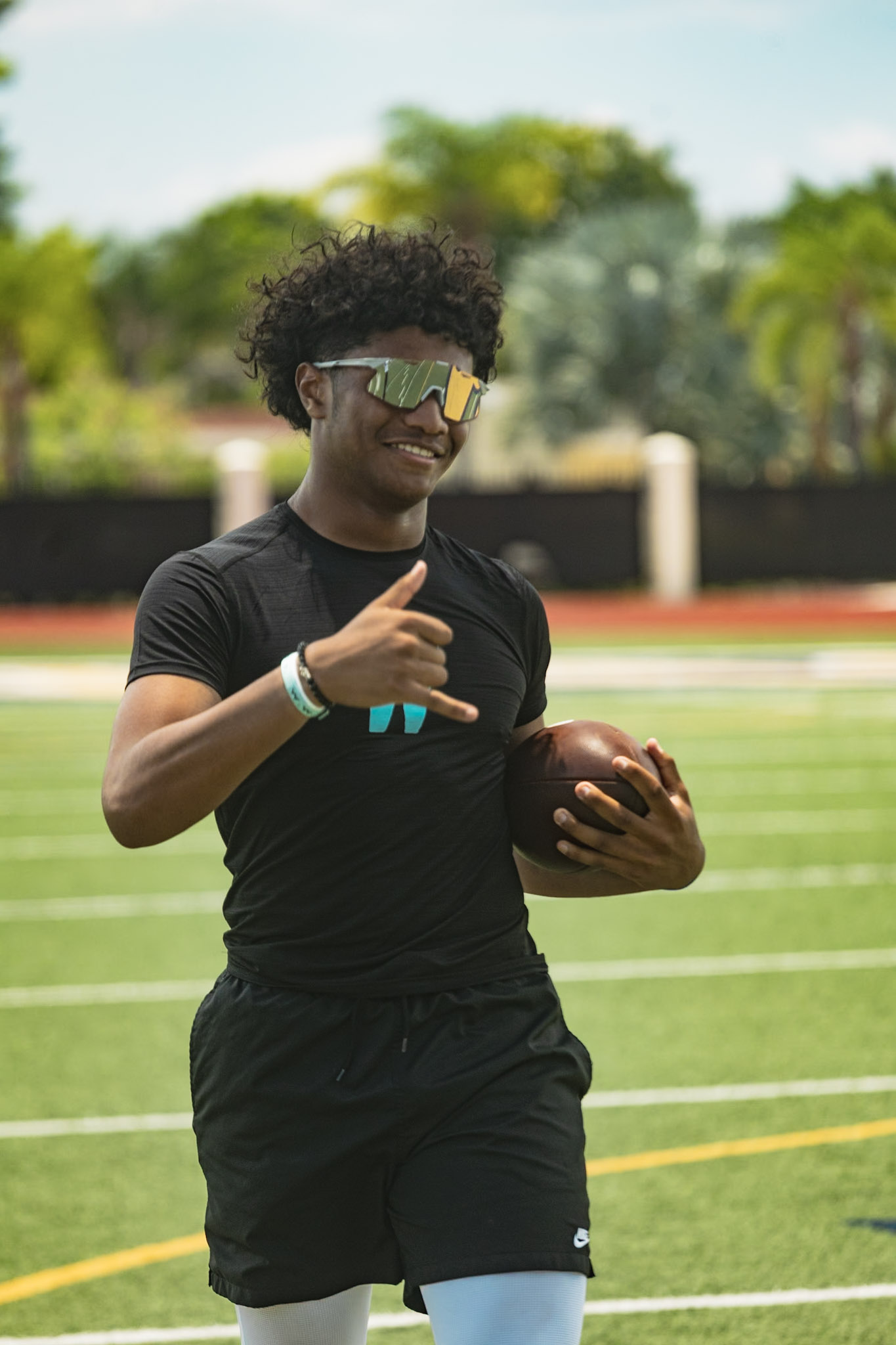 Trainer in a WeTrain tee holding a football on the sideline